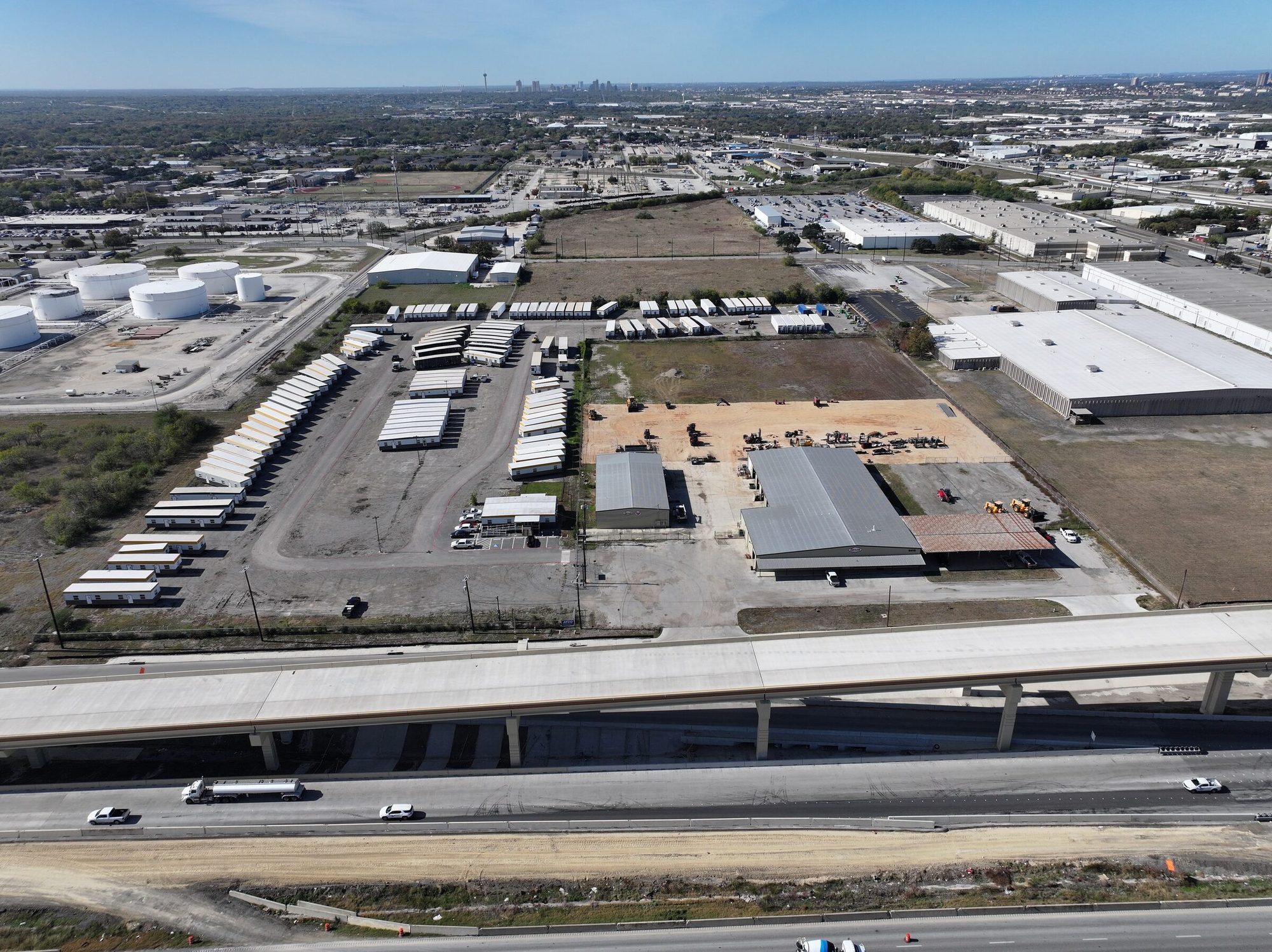 Aerial view of an industrial outdoor storage yard in San Antonio, Texas, with the downtown skyline in the distance